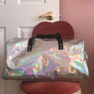 Holographic duffle bag with black straps.
